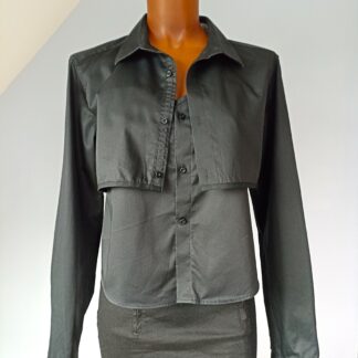 Ensemble caraco + cache-épaule noir. Caraco arrivant aux hanches. Photo sur mannequin vue de face. Le cache épaule est légèrement ouvert sur le caraco.