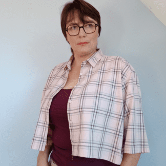 chemise crop top tartan portée ouverte sur un caraco bordeaux. Vue de trois quart. Crop top fond rose, imprimé écossais à lignes noires et grises