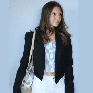 Veste noire courte, effet bombers. Col tailleur. Photo portée sur un jean blanc et top blanc et bleu. Vue face.